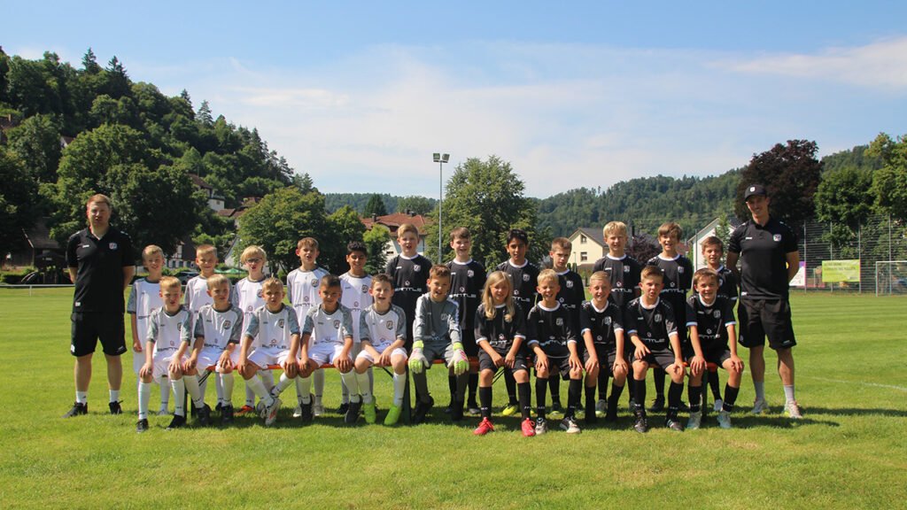 Spieler und Trainer der E-Jugend stehen versammelt auf dem Spielfeld.