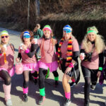 Sieben Frauen posieren in Kostümen zur Fasnet vor der Kamera. Sie haben Sonnenbrillen, Hüte, Röcke, Strumpfhosen und Schals an.