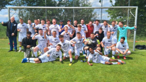 Die jubelnden Fußballer der Sportgemeinschaft Hochmössingen/Aistaig posieren auf dem Spielfeld vor dem Tor für ein Foto.