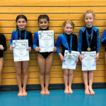 Eine Gruppe Mädchen steht mit Urkunden vor einer Holzwand