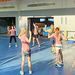 Trainerin führt Sportgruppe im Turnraum an.