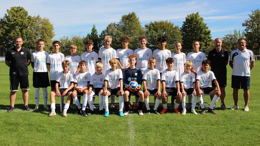 Spieler und Trainer der C-Jugend stehen versammelt auf dem Spielfeld.